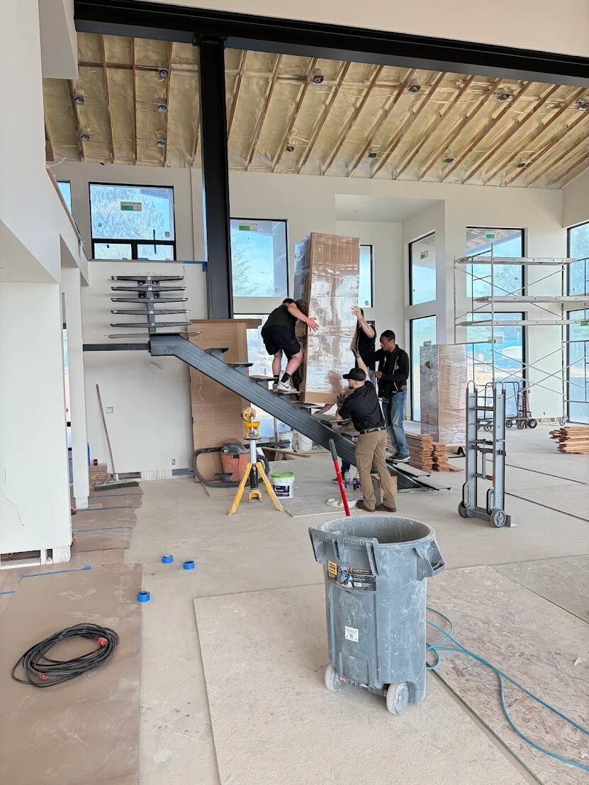 Move Forward LLC crew carefully moving a heavy item up a custom staircase in a Coeur d'Alene home